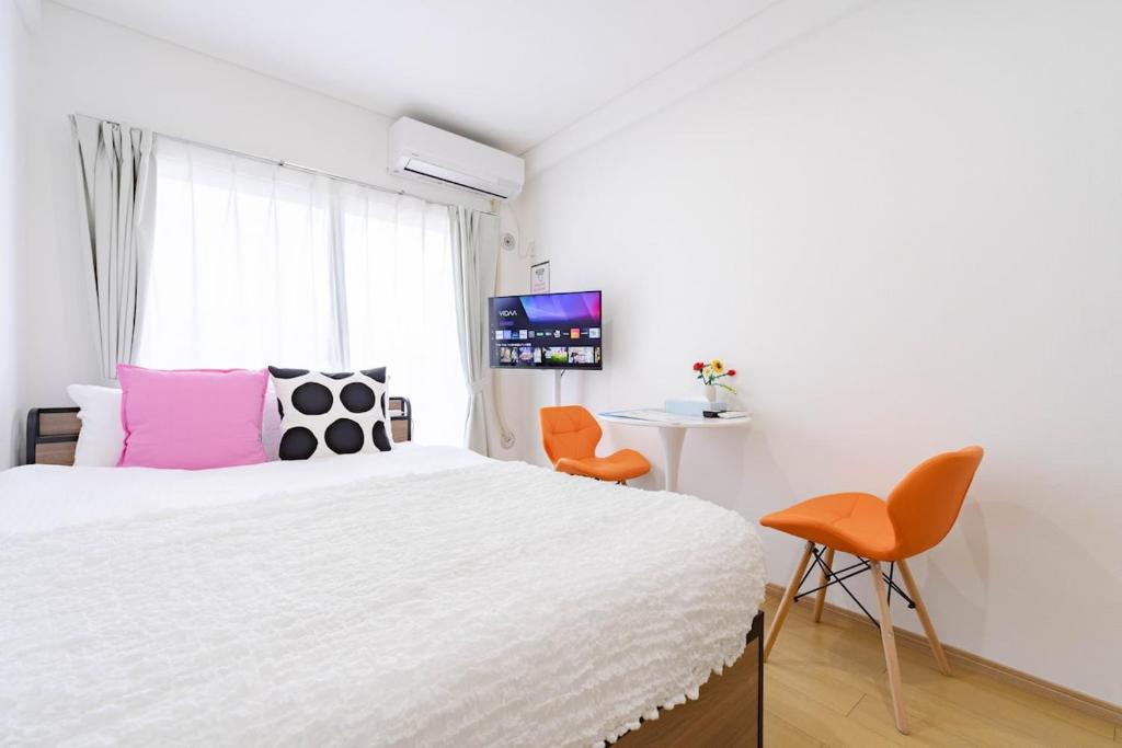 a bedroom with a large bed and orange chairs at アンドステイ屋形町704 in Kyoto