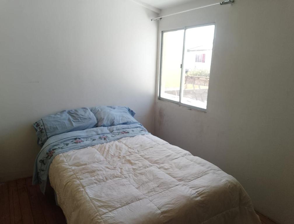a bed in a white room with a window at La Nave Coquimbo in Coquimbo