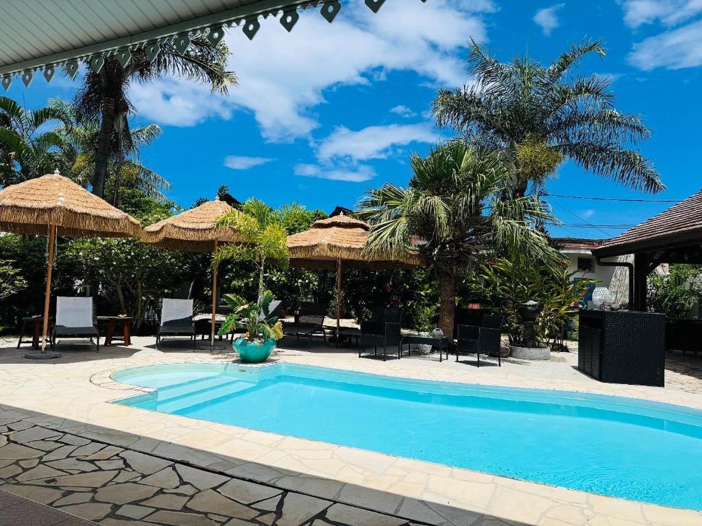 a swimming pool in a resort with umbrellas at Relais Fenua in Punaauia