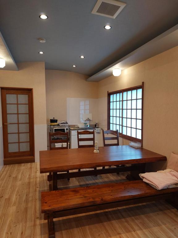 a living room with a wooden table and a kitchen at ゲストハウス凪季のやど in Nachikatsuura