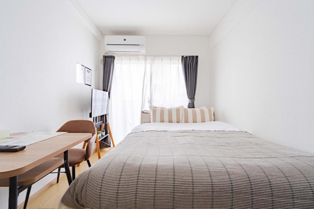 a bedroom with a bed and a table and a desk at アンドステイ屋形町507 in Kyoto