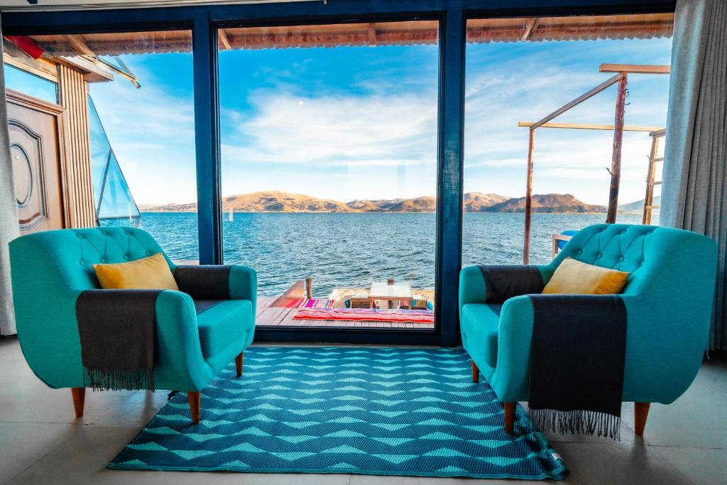 two chairs in a room with a view of the water at Uros Titicaca Lodge Puno in Puno