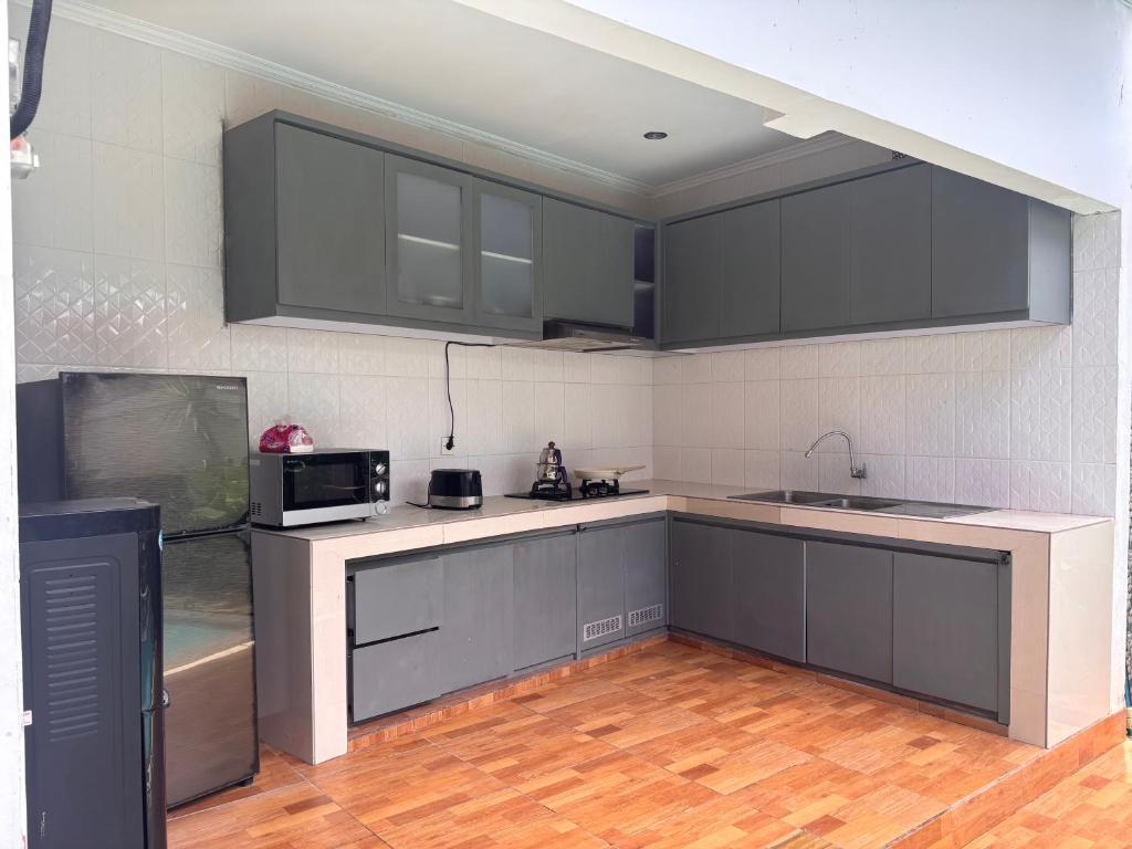 a kitchen with gray cabinets and a microwave at Villa lumbung sari in Cemagi