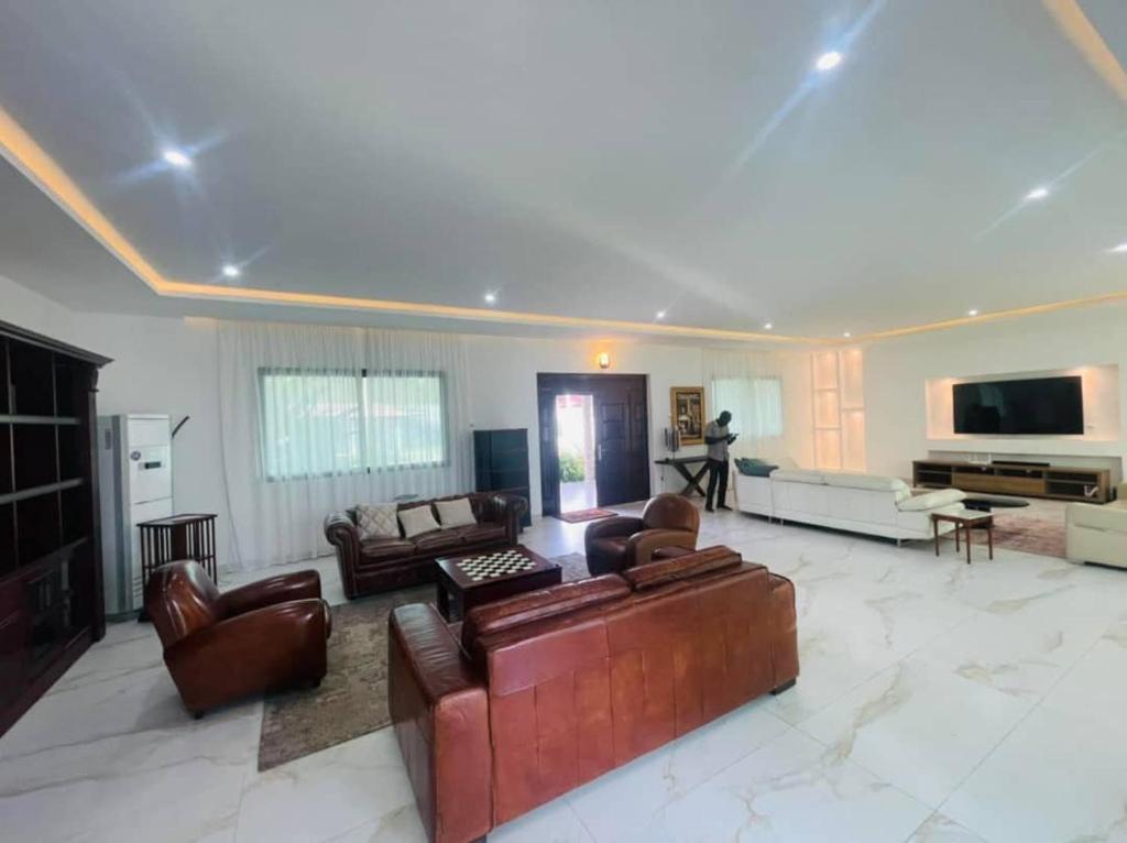a large living room with leather furniture and a television at villa zoum in Assinie