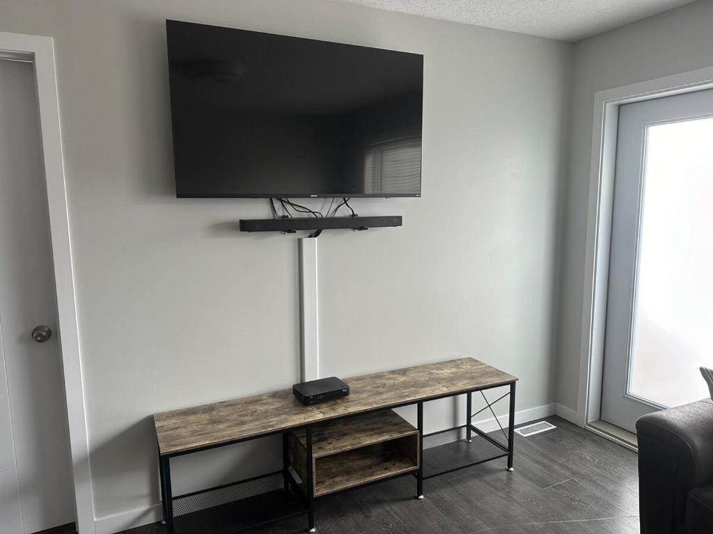 a room with a table with a television on a wall at Home Away from Home in Brandon
