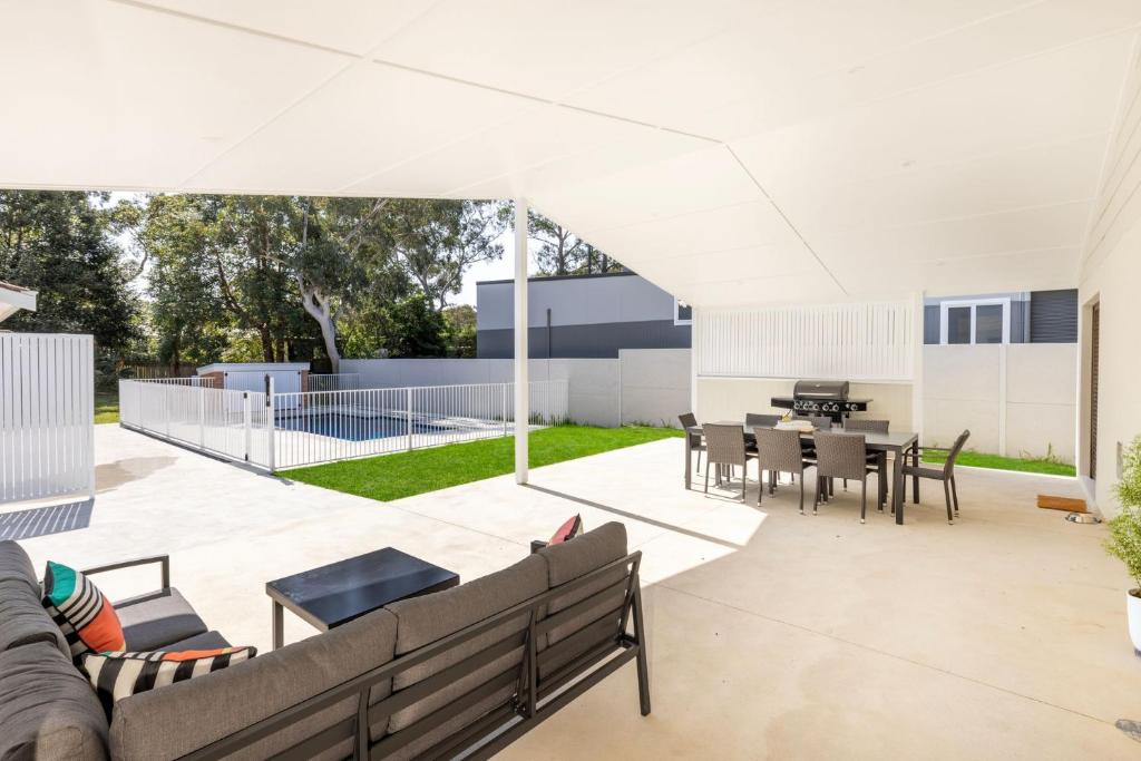 an outdoor patio with a couch and a table and chairs at Callala On King - Pet Friendly - Swimming Pool in Callala Beach