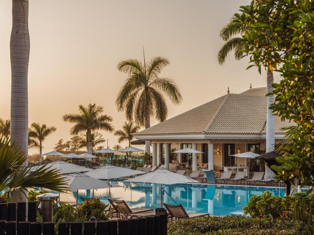a resort with a pool with chairs and umbrellas at RedLevel at Gran Meliá Palacio de Isora - Adults Only in Alcalá