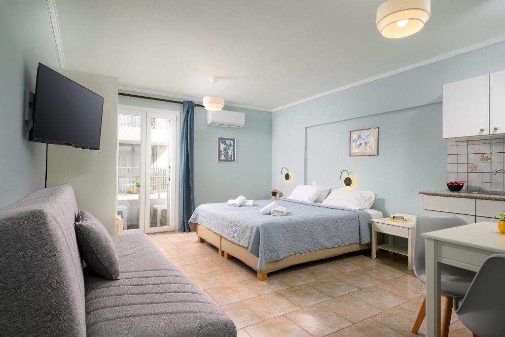 a bedroom with a bed and a couch and a tv at Aris Studios in Hersonissos