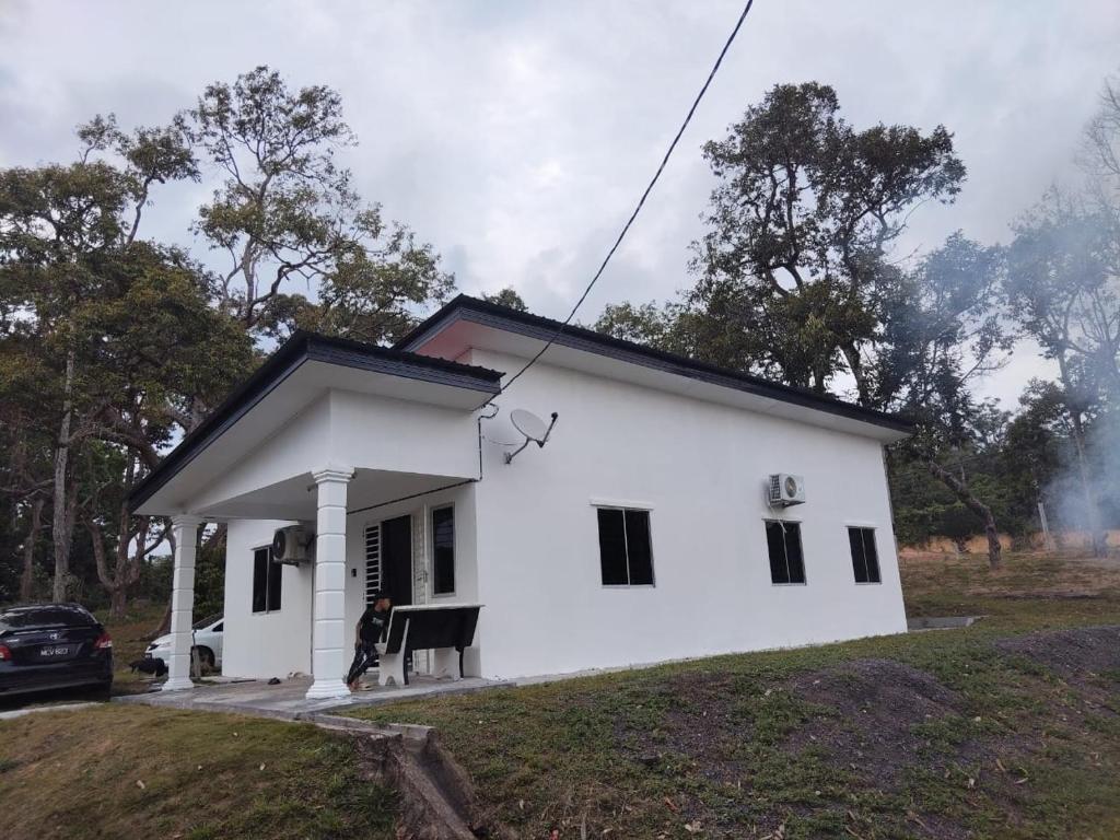 a white house with a person sitting in front of it at SHA HOMESTAY Budget in Tampin