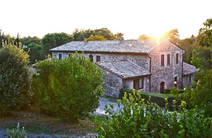 una gran casa de piedra en medio de un campo en Agriturismo Il Cornalino, en Castel Viscardo