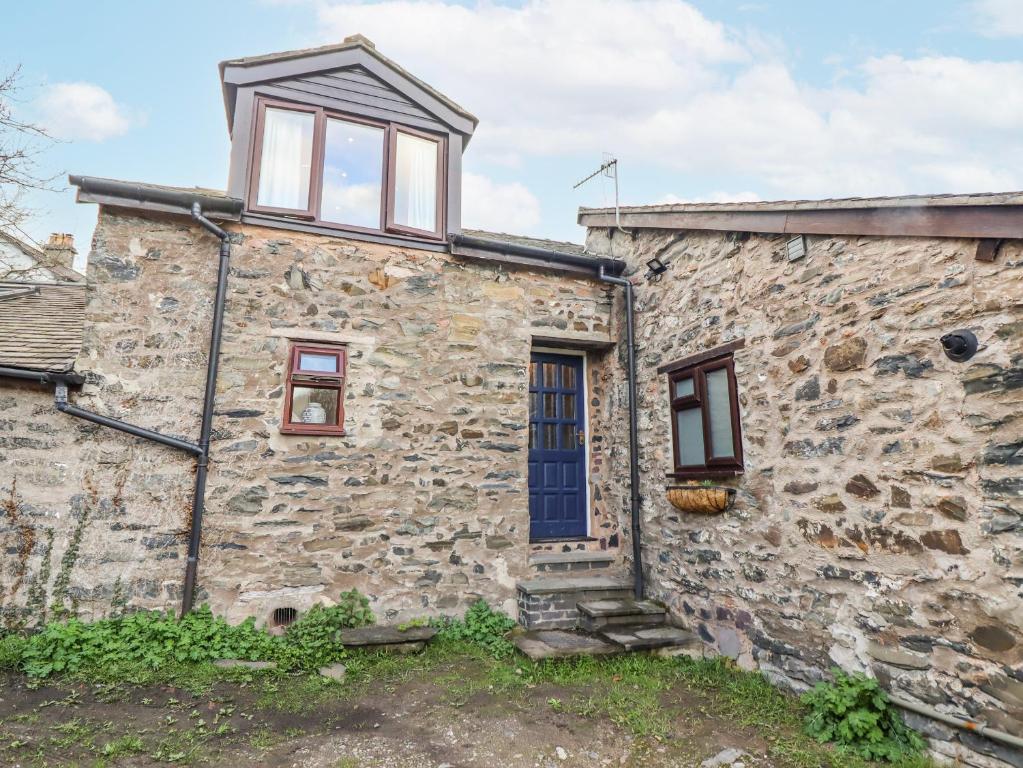 an old stone house with a blue door and windows at Dovetail Cottage in Llangollen
