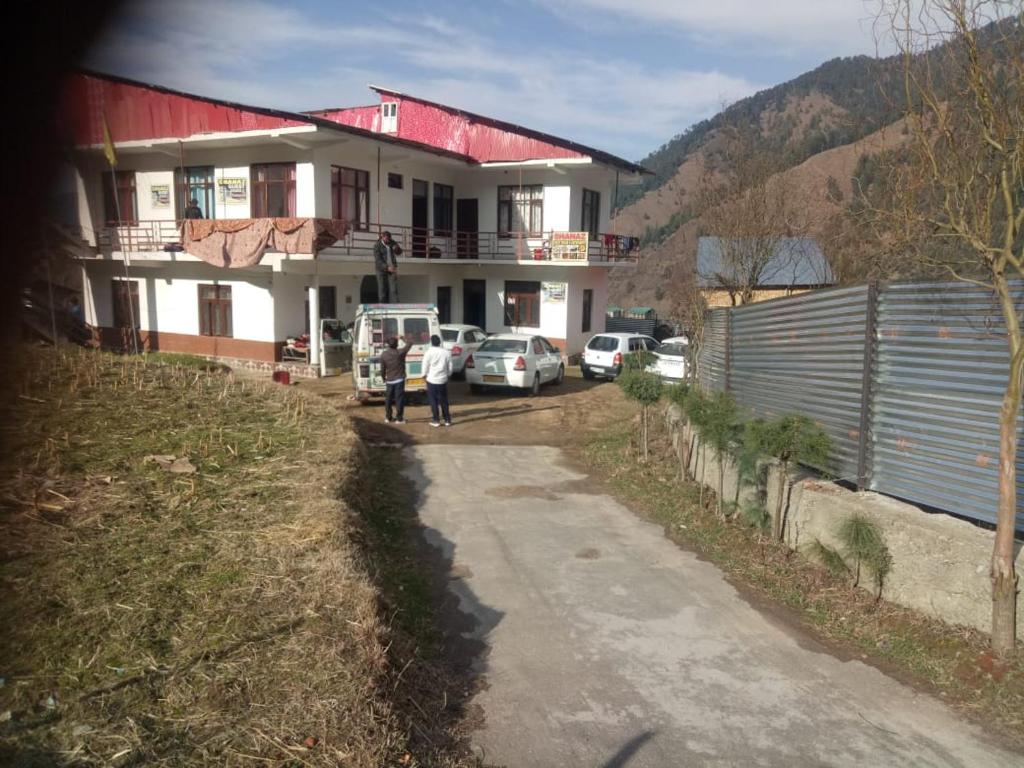 two people walking in front of a house at Bhaderwah Valley Resort in Bhadarwāh
