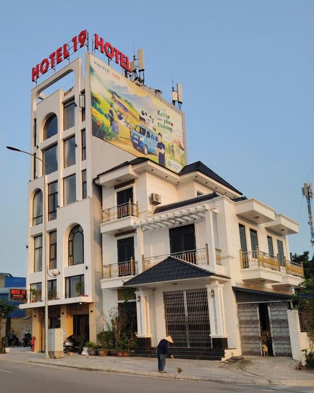 a man sweeping the street in front of a building at Hotel 19 in Mỹ Lộc