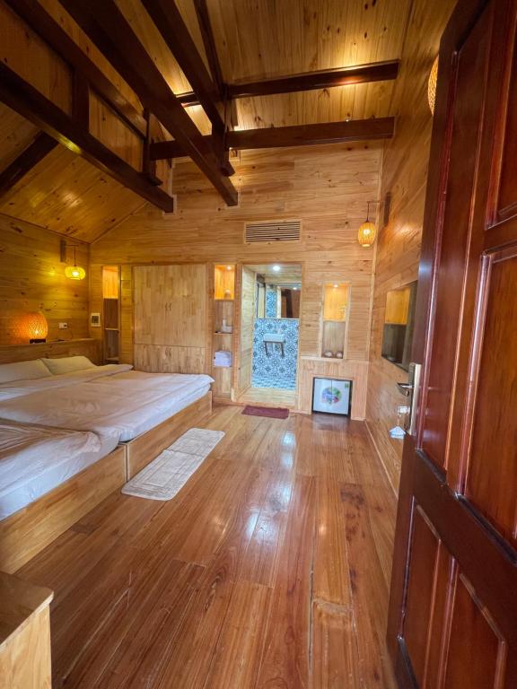 a large room with a bed and a wooden floor at Homestay Gió Mộc !! in Làng Môn
