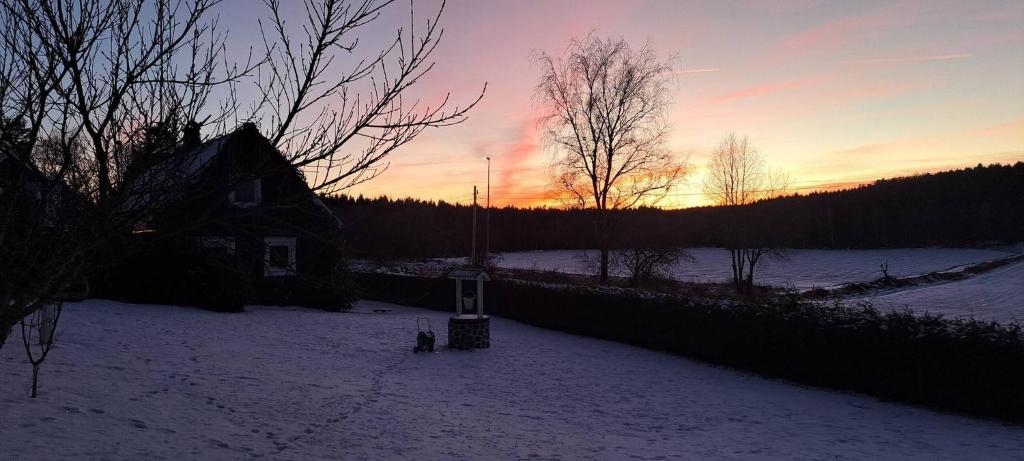 a house in the snow with the sunset in the background at Welcome to Lillstugan in Jämshög
