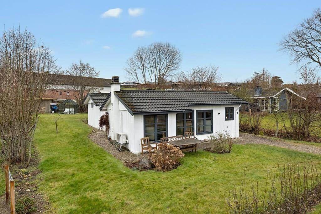 a small white house with a bench in a yard at SB122-Augustenborg-Gronvej-3 in Asserballeskov