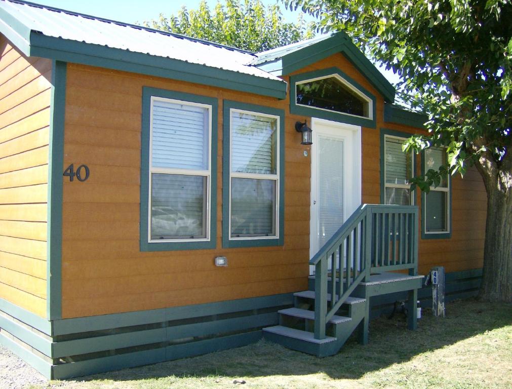 a tiny house with a porch and a staircase at Lake Minden Camping Resort Cottage 2 in Nicolaus
