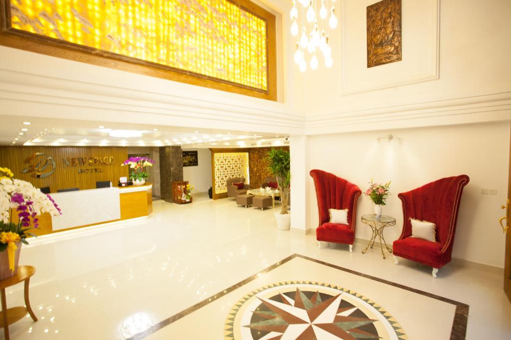 vestíbulo con sillas rojas y techo de vidrieras en New Space Hotel Airport, en Ho Chi Minh