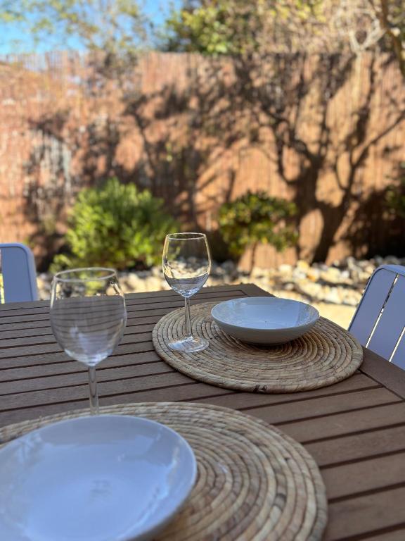 a wooden table with two glasses and plates on it at Caseta Cosi in Vic-la-Gardiole