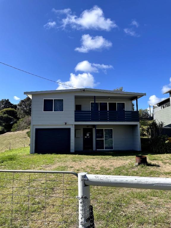 a white house with a fence in front of it at Saturn Parade Shack in Venus Bay
