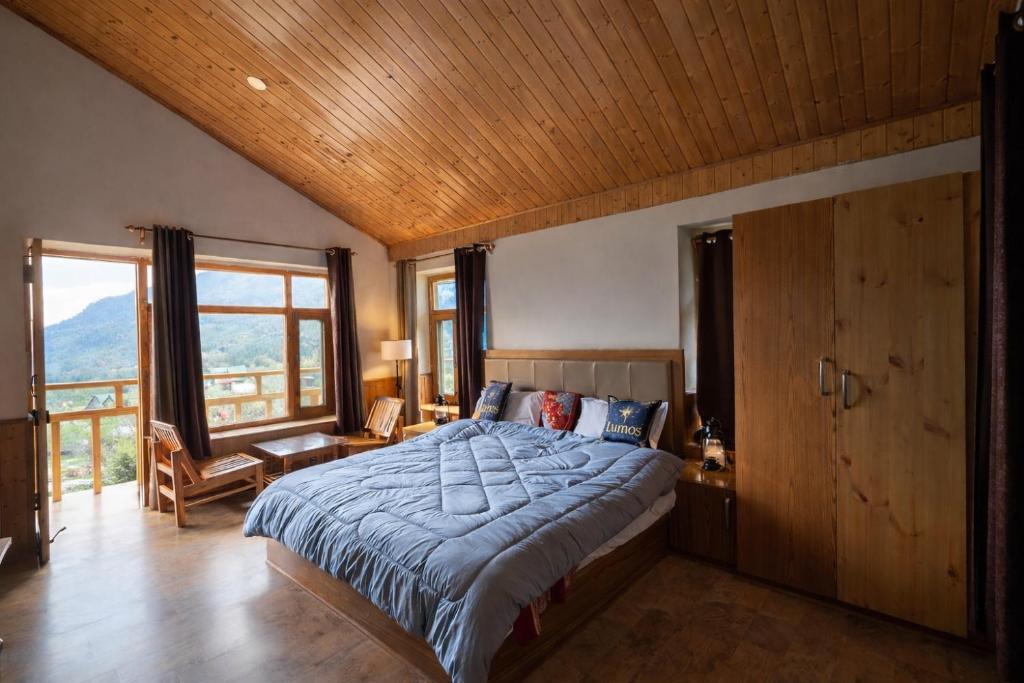 a bedroom with a large bed with a wooden ceiling at Hotter Potter Stays Manali in Vashisht