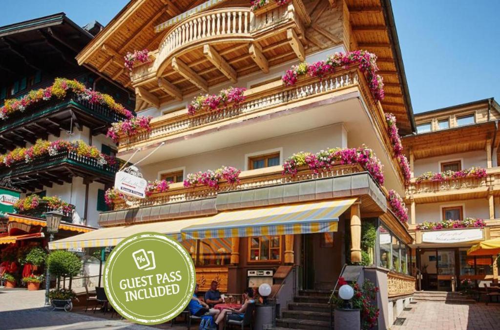a building with flower boxes and a sign in front of it at Hotel Wechselberger by Alpeffect Hotels in Saalbach-Hinterglemm