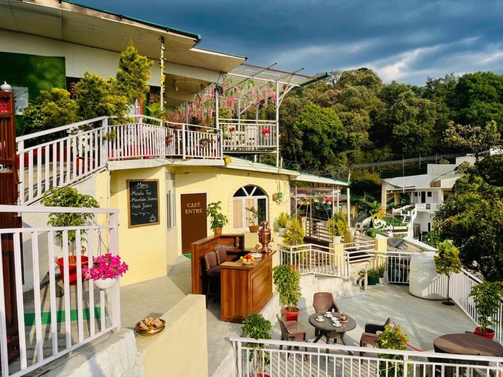 a balcony of a building with chairs and tables at Oliva by Quercus Oak Stays in Mussoorie