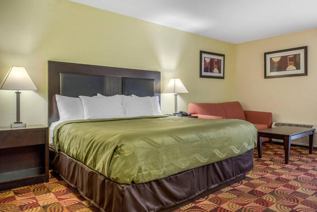 a hotel room with a bed and a chair at Quality Inn Bloomington Near University in Bloomington