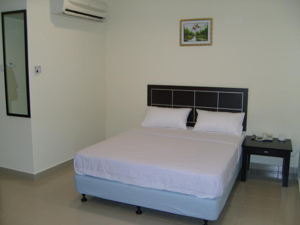 a bedroom with a large white bed with a black headboard at Hotel Orient in Johor Bahru