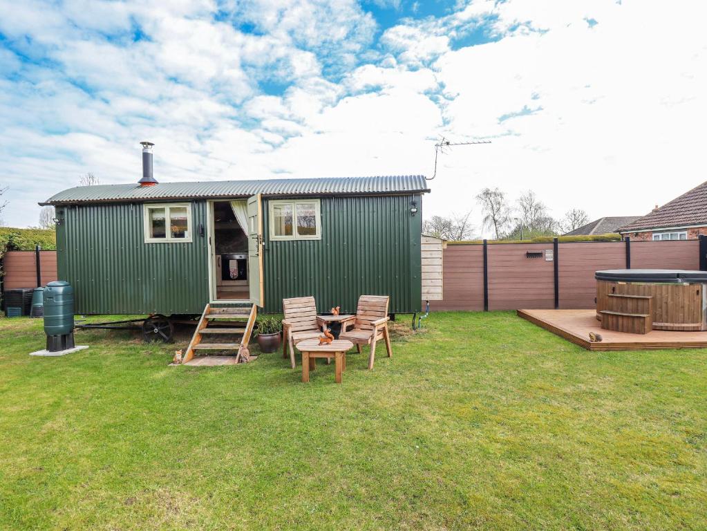 a green trailer with chairs and a table in a yard at Twit Twoo Shepherds Hut in Louth