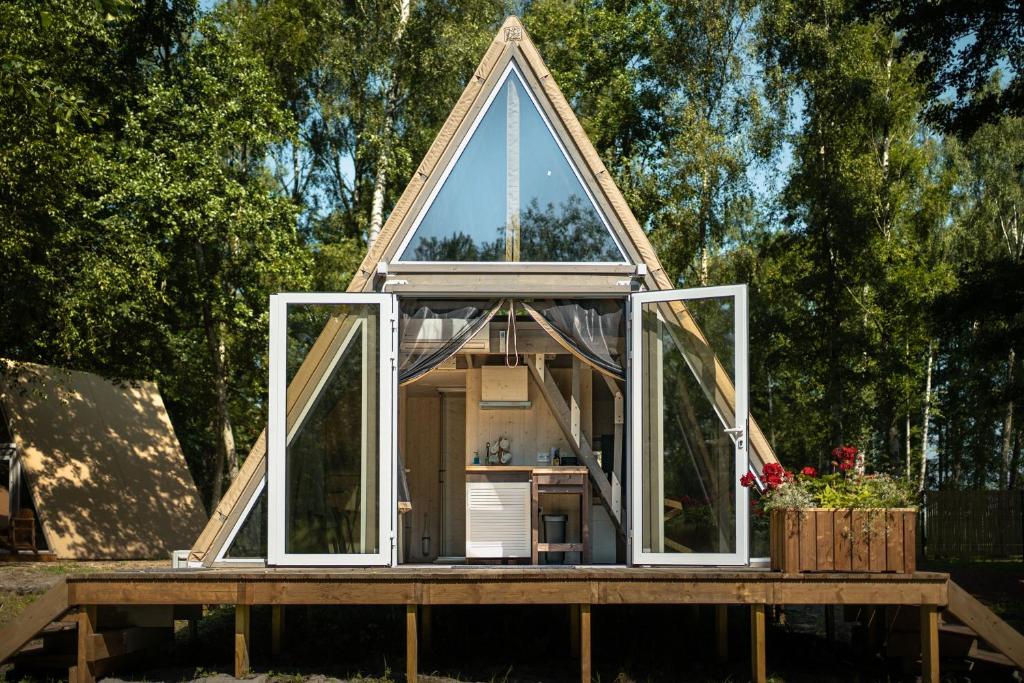 a frame house with windows on a wooden deck at Heaven Glamping - 300m from the Beach in Liepāja
