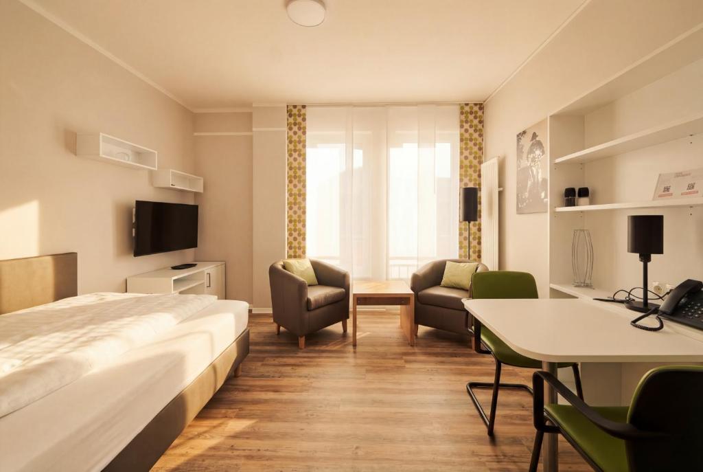 a hotel room with a bed and a desk and chairs at ADAPT APARTMENT HOTEL Siegen in Siegen