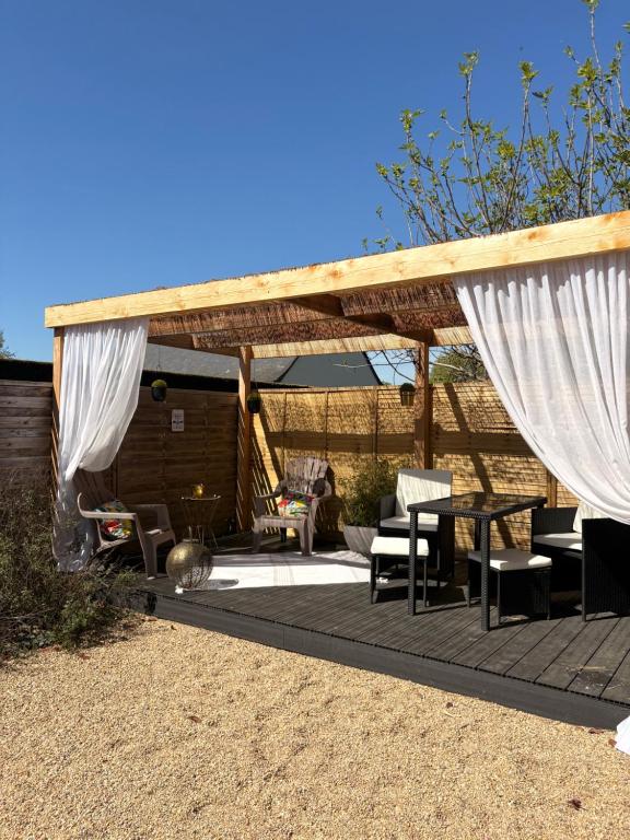 a patio with white curtains and a table and chairs at Maison Chez Marguerite in Saumur