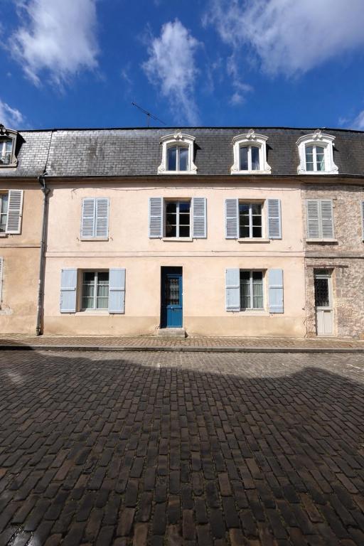 an old building with four windows and a blue door at Maison de campagne en plein centre de Senlis in Senlis