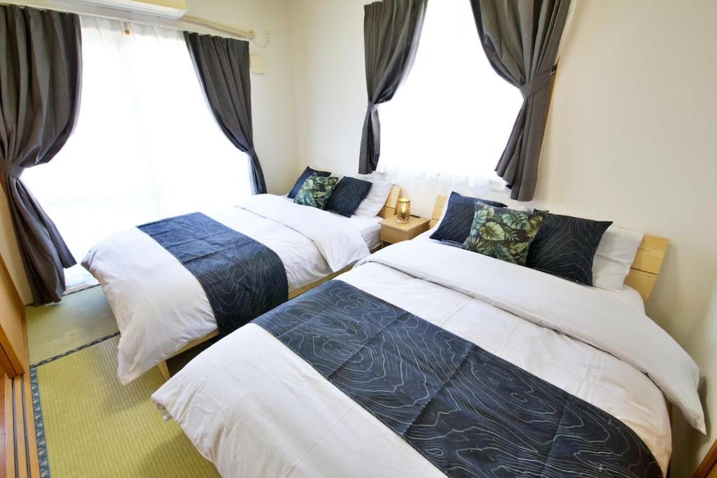 two beds in a room with a window at カラハーイもとぶ 碧 in Motobu
