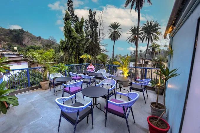 a patio with tables and chairs and palm trees at Boho Villa Mount Abu in Mount Ābu