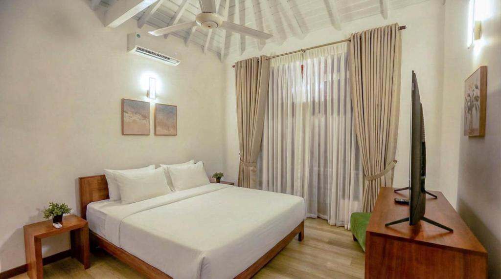 a bedroom with a large white bed and a table at Villa Barracuda in Sri Jayewardenepura Kotte