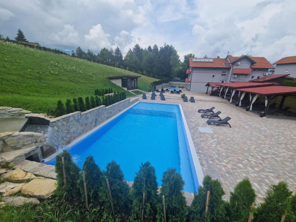 a large swimming pool in a yard with a hill at Plitvice Palace Rooms - Adults Only in Grabovac