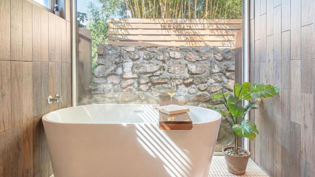 a bath tub in a bathroom with a stone wall at gyeongju planb pet pension in Gyeongju