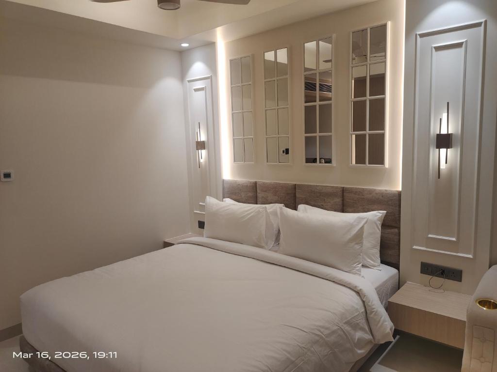 a bedroom with a white bed with white pillows at Shagun Hotel & Resorts in Khandwa