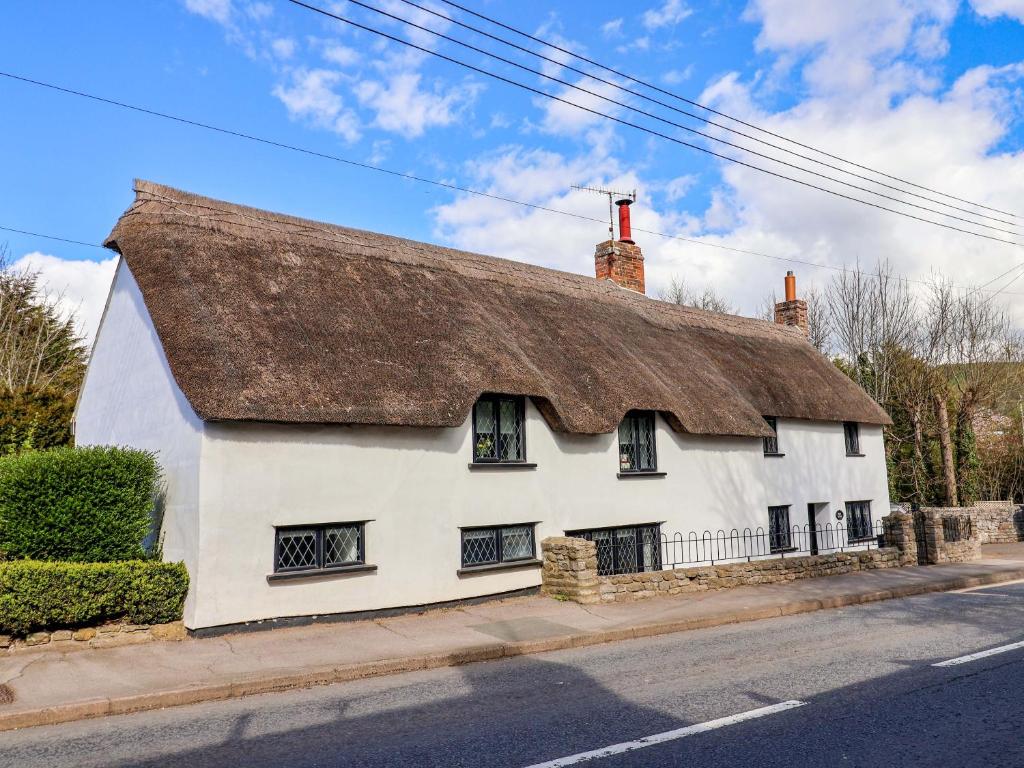 a white house with a thatched roof on a street at Bridge Cottage in Bridport
