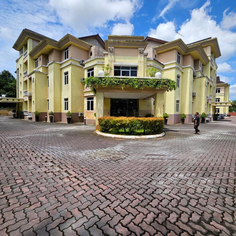 a large yellow building on a brick street at Song Service Apartment formerly known as Jinhold Service Apartment in Kuching