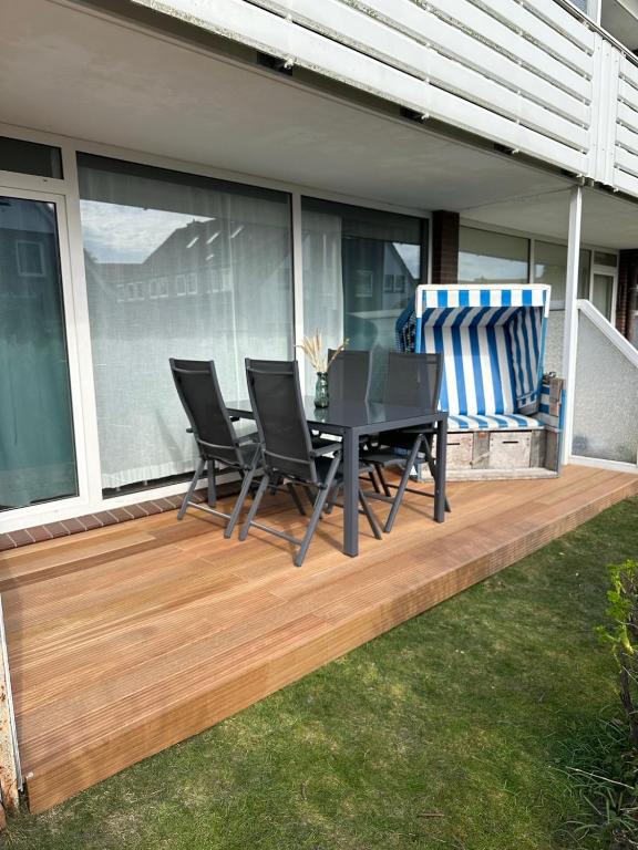 a deck with chairs and a table on a house at Komodig in Langeoog