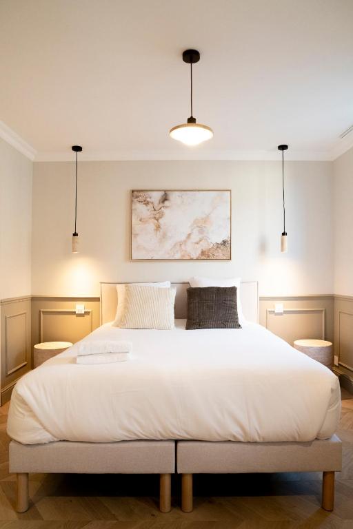 a bedroom with a large white bed with two pillows at Studio haut de gamme - Hypercentre - Lit Queen in Caen