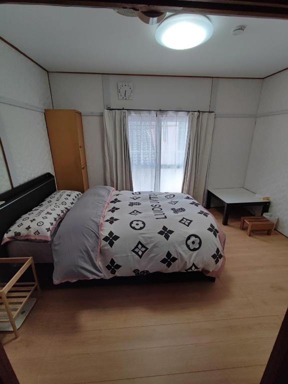 a bedroom with a bed in a room with a window at 天王寺まで電車にて 約10分 福宿八尾 in Yaochō