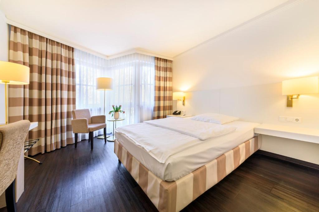 a hotel room with a large bed and a desk at relexa hotel Schatten Stuttgart in Stuttgart