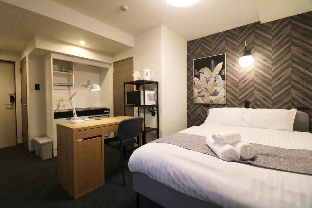 a hotel room with a bed and a desk at TAKETO STAY PREMIERE SAPPORO EKi in Sapporo