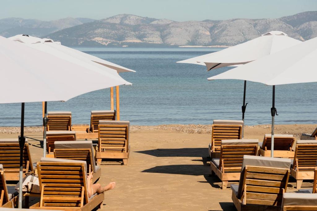 a group of chairs and umbrellas on a beach at Ionian Blue Beach Hotel - Adults Only in Kavos