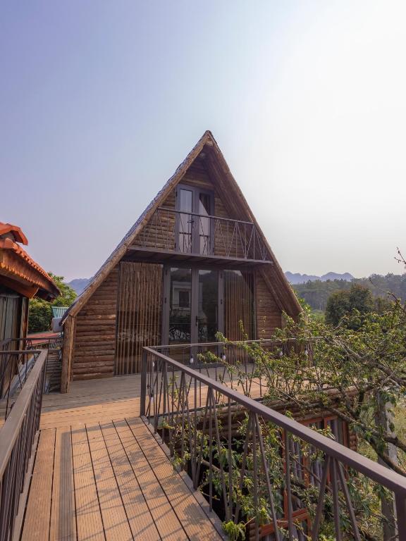 a house with a thatched roof and a wooden deck at Homestay Gió Mộc !!! in Làng Môn