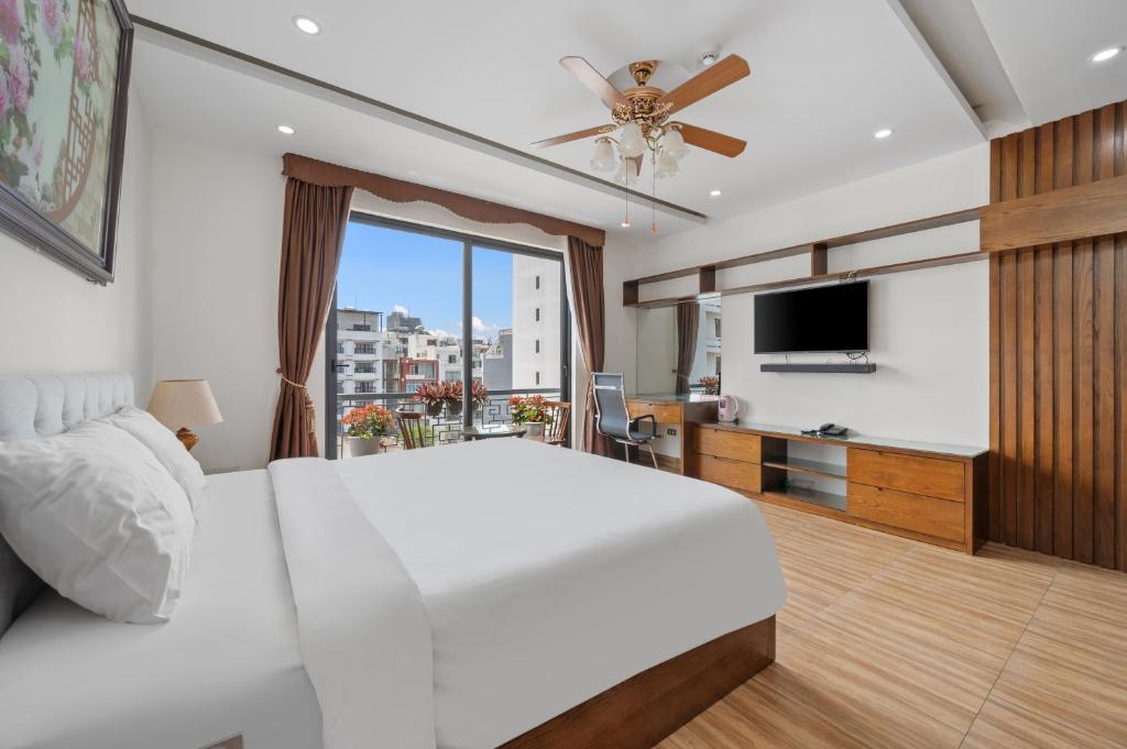 a bedroom with a white bed and a ceiling fan at AVA Hotel & Apartment in Danang